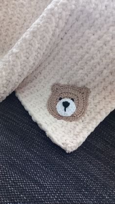 a knitted teddy bear on the back of a white sweater with a blue nose