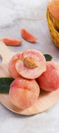 peaches on a wooden plate with leaves and a basket in the backgroud