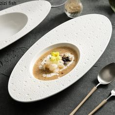 two white plates topped with food next to spoons and utensils on a table