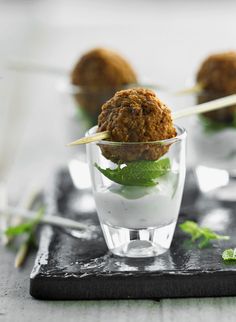 small appetizers with toothpicks in glass cups on black slate serving tray