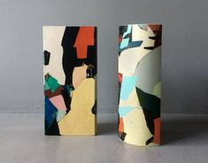 two vases sitting next to each other on top of a gray floor covered in paint