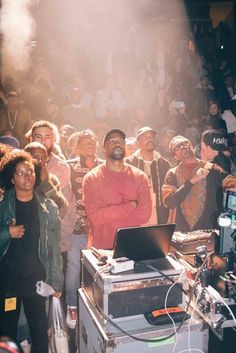 a man standing in front of a dj set with people watching from the sidelines