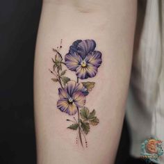 a woman's thigh with purple flowers and leaves on the side, in front of her leg