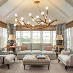 a living room filled with furniture and a chandelier hanging over the top of it