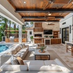 an outdoor living area with couches and tables next to a swimming pool in the background