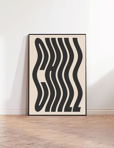 a black and white abstract art piece sitting on top of a hard wood floor