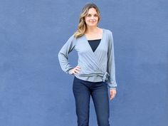 a woman standing in front of a blue wall with her hands on her hips and looking at the camera