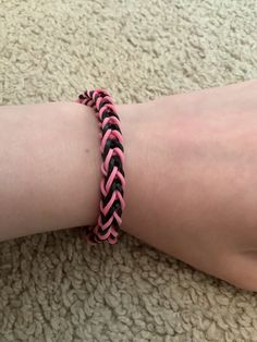 a pink and black braided bracelet on someone's arm