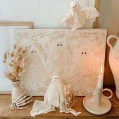 three ghost figurines sitting on a table next to a vase and candle holder