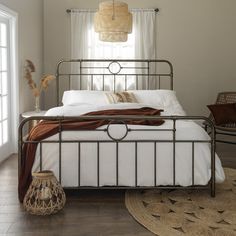 a bed with white sheets and pillows in a bedroom next to a rug on the floor