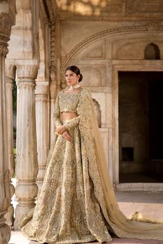 a woman in a gold colored lehenga and matching blouse is posing for the camera