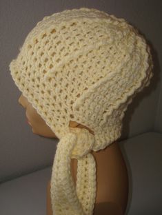 a crocheted hat on top of a mannequin's head with a scarf around it