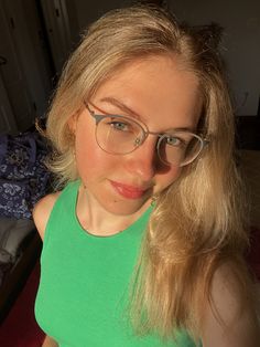 a woman with glasses is taking a selfie in front of the camera while wearing a green tank top