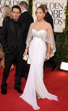 a man and woman in formal wear standing on a red carpet at the golden globe awards