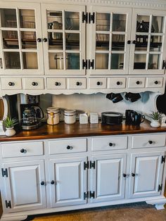 a kitchen with white cabinets and wooden counter tops, including a coffee maker on top