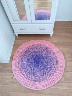 a pink and purple rug sitting on top of a wooden floor next to a white cabinet