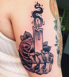 a woman's arm with a candle and roses tattoo on the left side of her shoulder