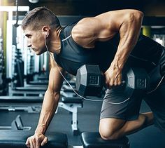 a man is doing exercises with dumbbells in the gym while listening to music