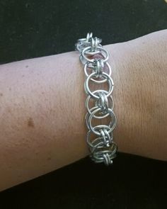 a person's arm with a silver chain bracelet on it