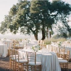 there are many tables and chairs with white linens on them at this wedding reception