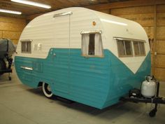 an old blue and white trailer parked in a garage