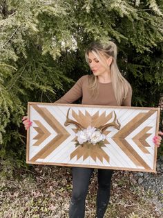 a woman holding up a large wooden sign with an animal's head on it