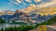 a scenic view of mountains and trees with clouds in the sky above them at sunset