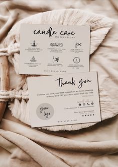 two thank cards on top of a bed next to a roped up pillow and blanket