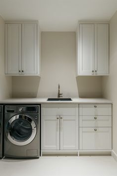 a washer and dryer in a small room with white cabinets on the walls