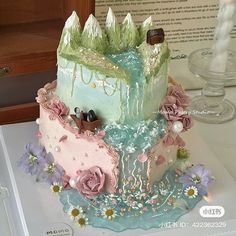 a three tiered cake decorated with flowers and frosting on top of a table