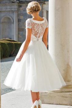 a woman in a white dress is standing on some steps with her back to the camera