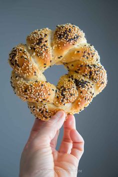 a person holding up a sesame seed bagel