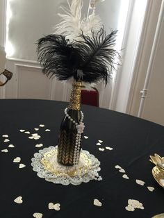 a table topped with a vase filled with feathers and beads on top of a black table cloth