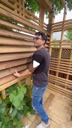 a man standing on top of a wooden deck next to a planter filled with green plants