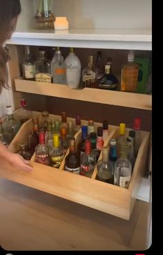 a man standing in front of a cabinet filled with liquor bottles