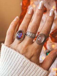 a woman's hand with three rings on it and a christmas tree in the background