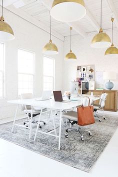 a white table and chairs in a room with lights hanging from the ceiling above it