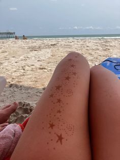 a woman laying on top of a sandy beach next to the ocean covered in sunburnts