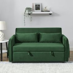 a green couch sitting on top of a white rug next to a table and lamp