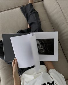 a person laying on a couch holding two books