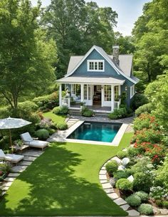 a small pool surrounded by lush green grass and trees, next to a white house