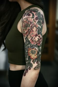 a woman's arm with flowers and leaves on it