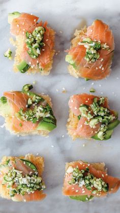 sushi rolls with cucumber and sesame seeds on top are arranged in rows