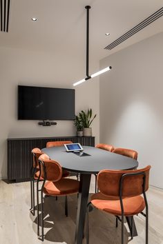 an office meeting room with orange chairs and a flat screen tv mounted on the wall