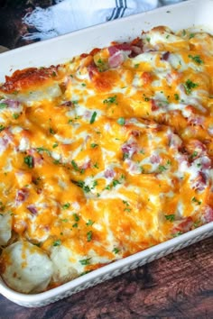 a casserole dish with potatoes, ham and cheese in it on a wooden table