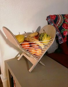 a basket filled with fruit sitting on top of a wooden table next to a pillow