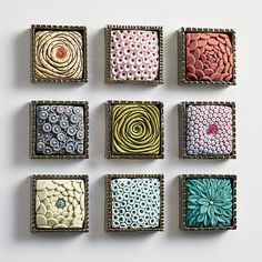 six square trays with different designs in them on a white surface, each containing an individual's own design