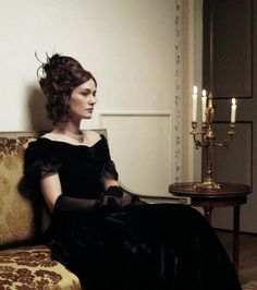 a woman in a black dress sitting on a couch