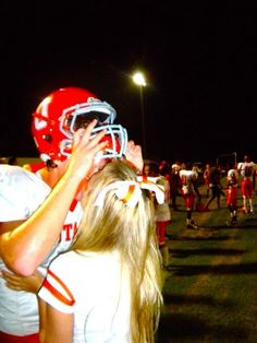 the football players are hugging each other on the sidelines at night, with lights in the background