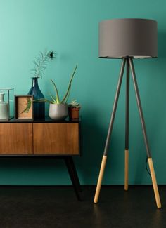 a wooden table topped with a lamp next to a green wall